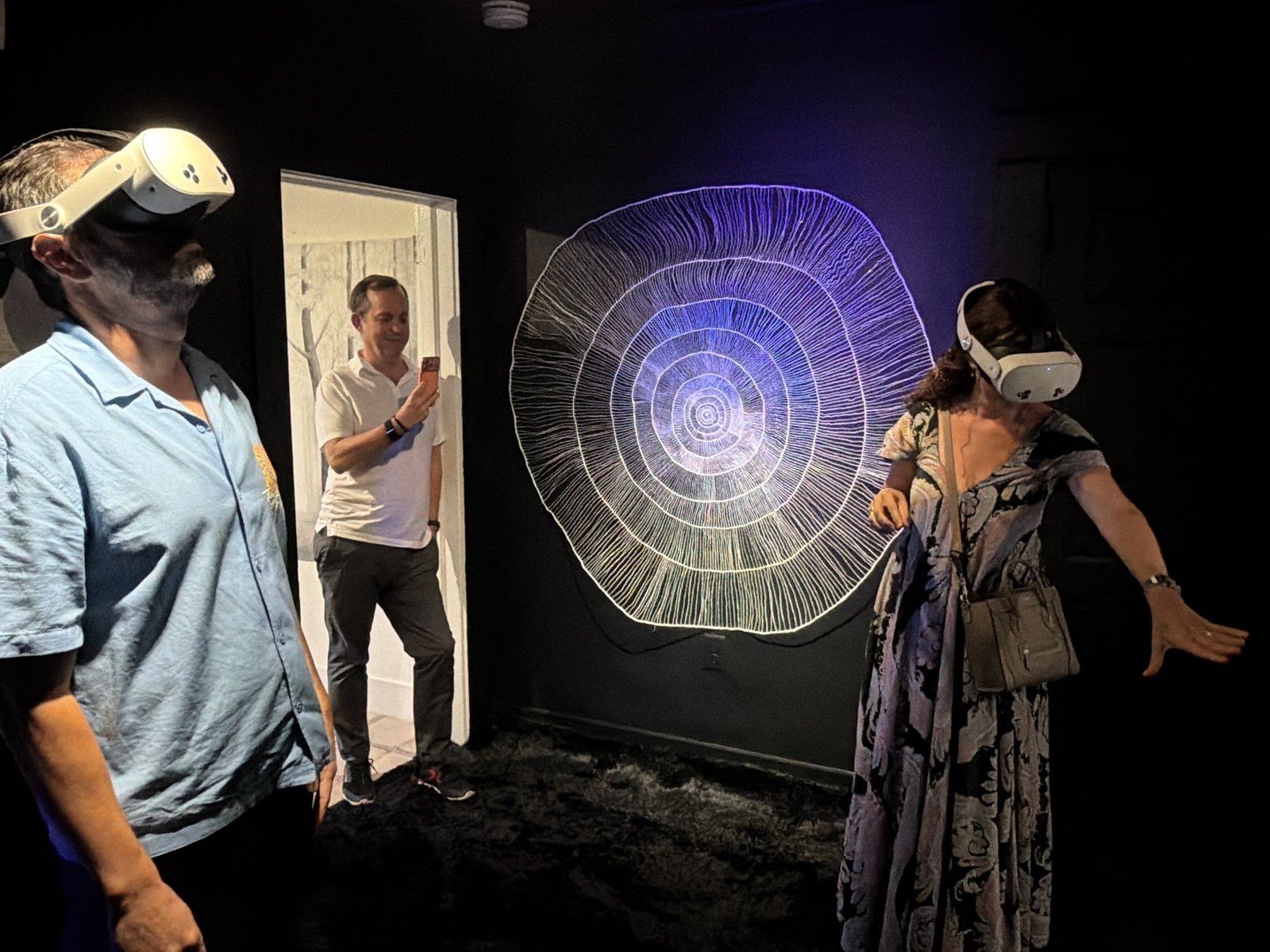 Two visitors in headsets beside a large circular Hyperspace drawing under ultraviolet light at Tower Artist Studios, Miami