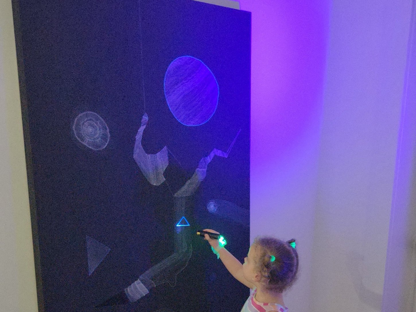 A young visitor lights a Hyperspace drawing with an ultraviolet torch at Tower Artist Studios, Miami